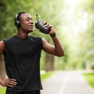 man drinking water after a park run