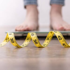 man standing on a scale with a measuring tape on the floor