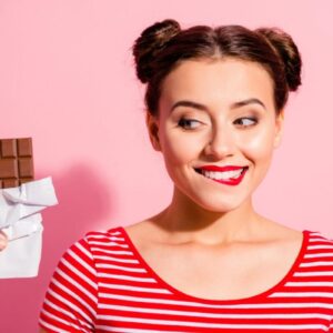 women in front of pink wall looking excitedly at a chocolate bar